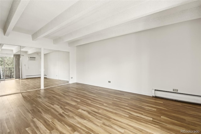 basement featuring a baseboard heating unit, wood finished floors, and a wall mounted AC