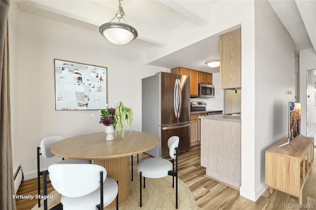 dining space with baseboards, light wood finished floors, and a baseboard heating unit