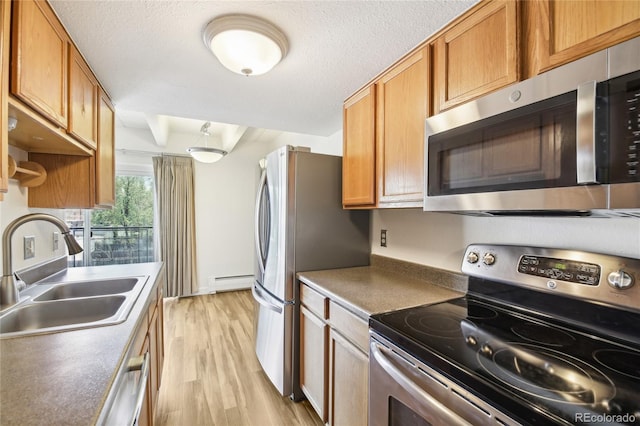 kitchen with brown cabinetry, a sink, a baseboard heating unit, light wood-style floors, and stainless steel appliances