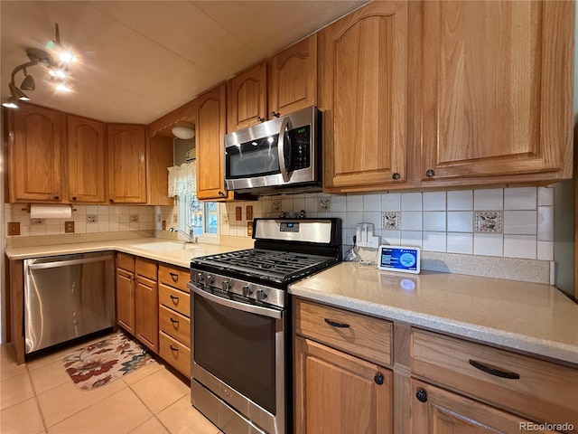 21300 County Road 13, La Jara, CO 81140 - kitchen with a sink, decorative backsplash, appliances with stainless steel finishes, brown cabinets, and light tile patterned floors