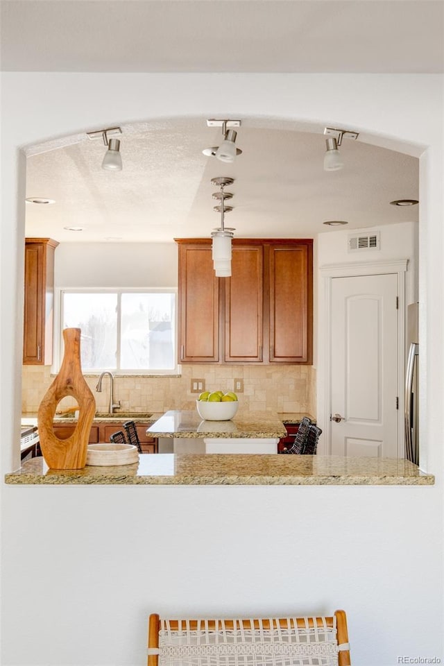 kitchen featuring light stone countertops, kitchen peninsula, and decorative backsplash