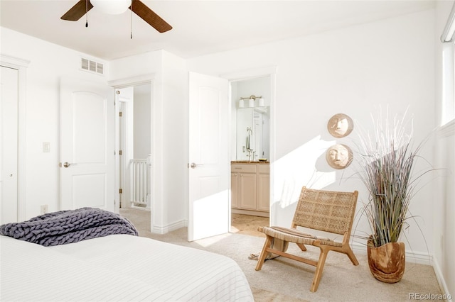 bedroom featuring light colored carpet, ceiling fan, and ensuite bathroom