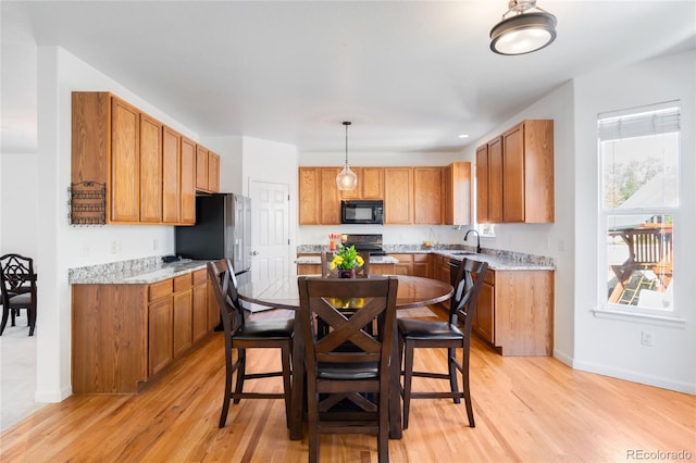 5861 Mt Shadows Blvd, Firestone, CO 80504 - kitchen with black microwave, light wood finished floors, a sink, range, and brown cabinets