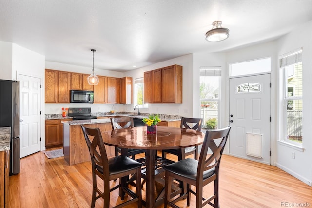 5861 Mt Shadows Blvd, Firestone, CO 80504 - kitchen with black appliances, brown cabinets, light wood-style floors, light stone countertops, and pendant lighting
