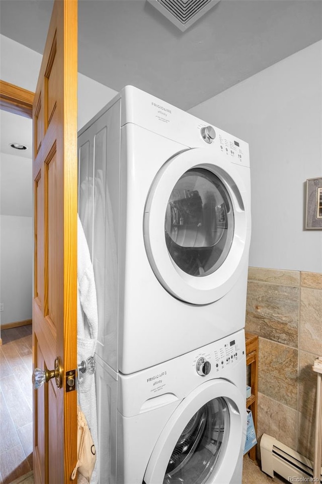 9045 W Ithaca Pl, Denver, CO 80235 - washroom with stacked washer / dryer, a baseboard radiator, and wood finished floors