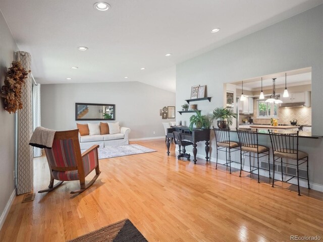 living area with light wood finished floors, recessed lighting, baseboards, and lofted ceiling