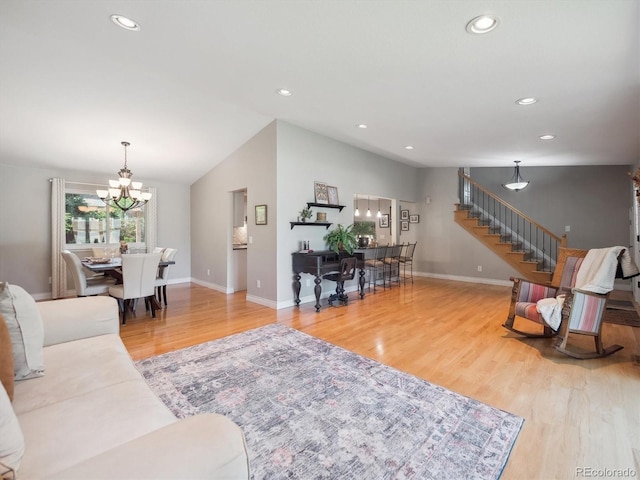 living area with a chandelier, wood finished floors, baseboards, stairs, and vaulted ceiling