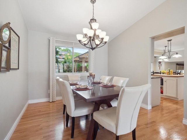 dining area with a chandelier, light wood finished floors, and baseboards