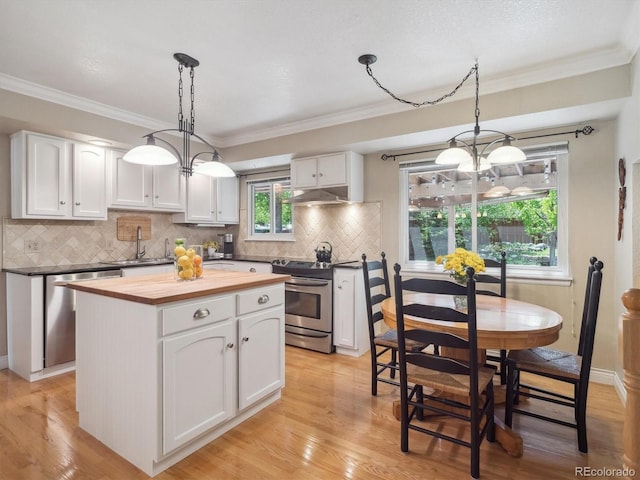 kitchen with wood counters, stainless steel appliances, a chandelier, white cabinets, and ornamental molding