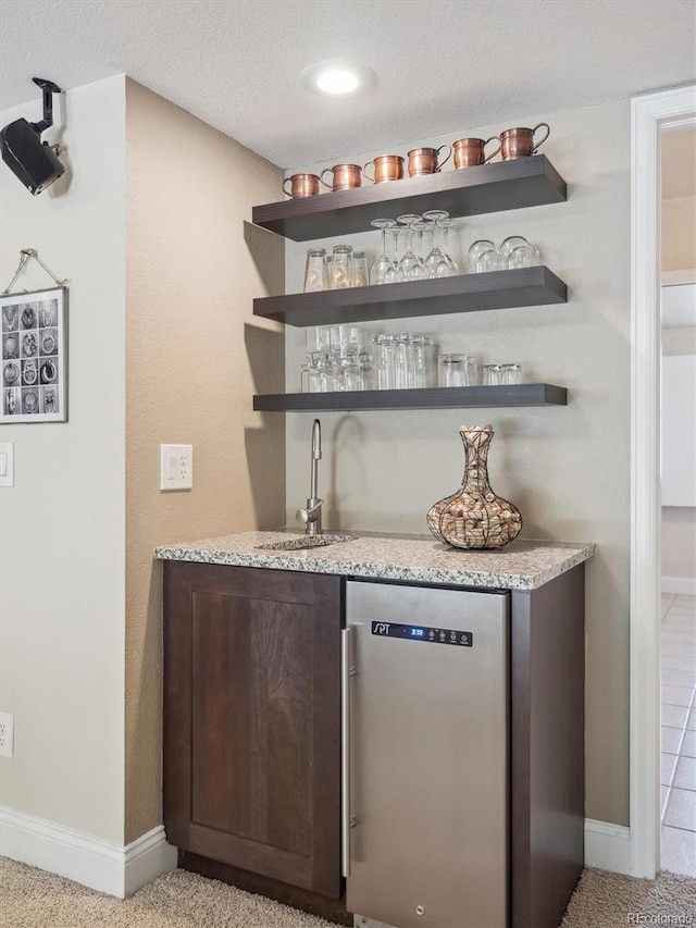 indoor wet bar with baseboards, dishwasher, and a textured ceiling