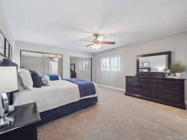 bedroom featuring multiple closets, baseboards, light carpet, and ceiling fan
