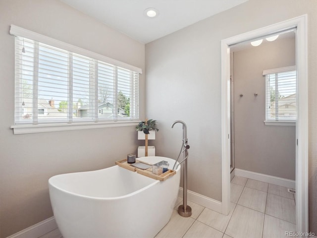 full bath featuring tile patterned flooring, a soaking tub, baseboards, and a shower stall