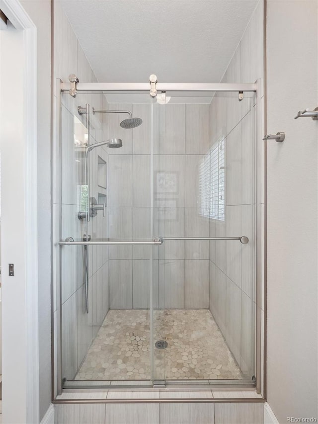 bathroom with a shower stall, baseboards, and a textured ceiling