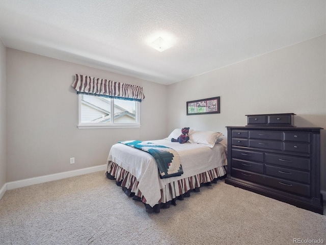 carpeted bedroom featuring baseboards and a textured ceiling