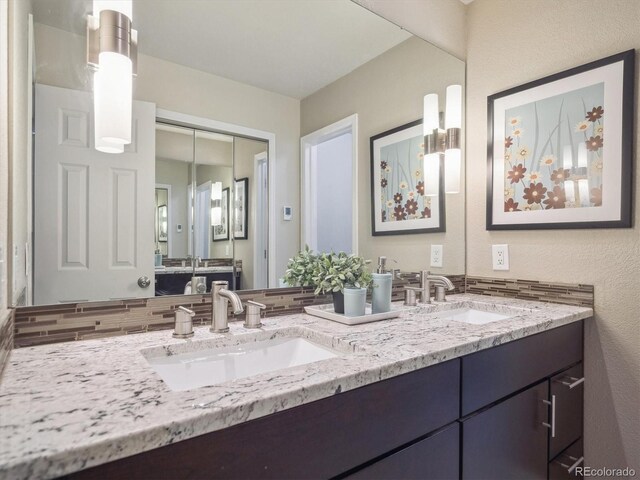 full bath with double vanity and a textured wall