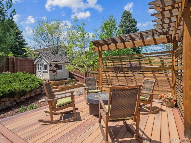 wooden deck featuring a storage unit, a fenced backyard, an outbuilding, and a pergola