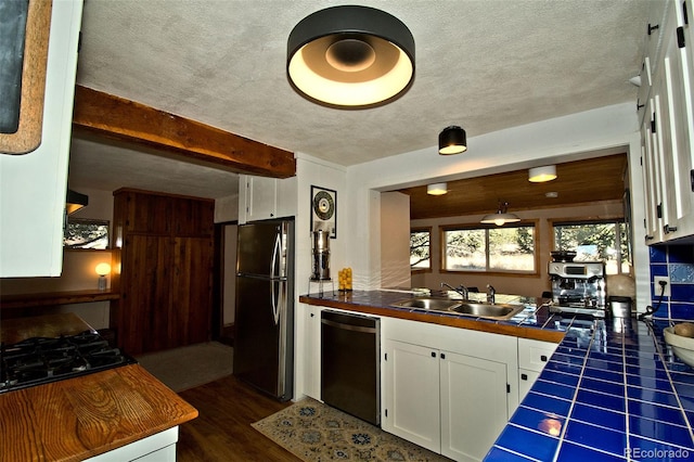 kitchen with white cabinets, sink, dark hardwood / wood-style floors, appliances with stainless steel finishes, and tile counters