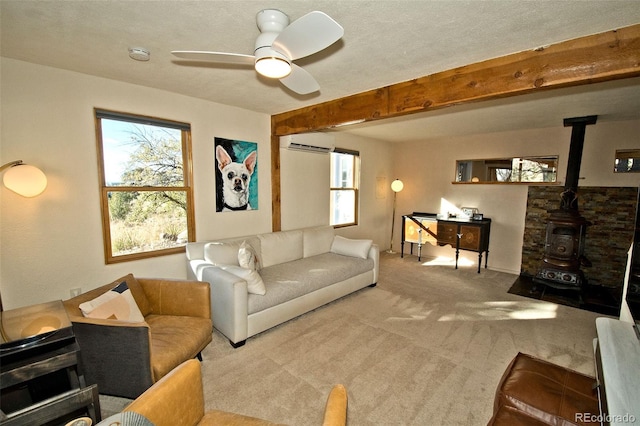 living room with beam ceiling, a wood stove, ceiling fan, an AC wall unit, and light carpet