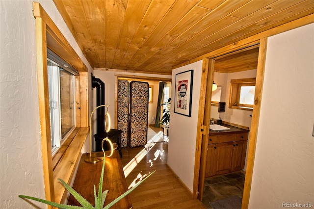 hall with hardwood / wood-style floors, wooden ceiling, and sink