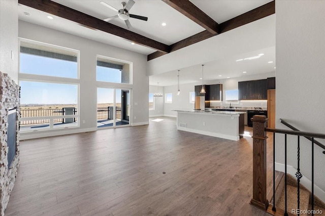 living room with beamed ceiling, dark hardwood / wood-style floors, ceiling fan, and a towering ceiling