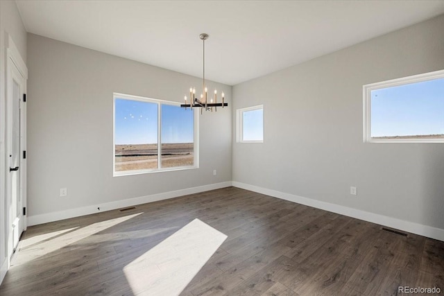 spare room featuring hardwood / wood-style flooring and a chandelier