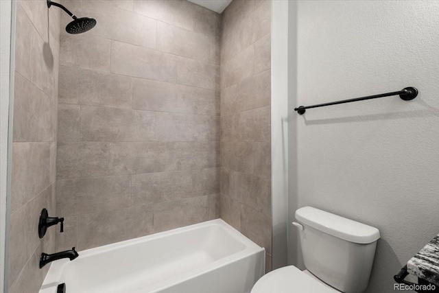 bathroom featuring tiled shower / bath combo and toilet