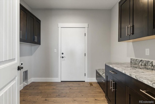 clothes washing area with light hardwood / wood-style flooring and cabinets