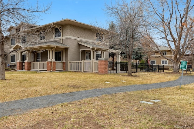 exterior space with a fenced front yard, a porch, a front lawn, and brick siding