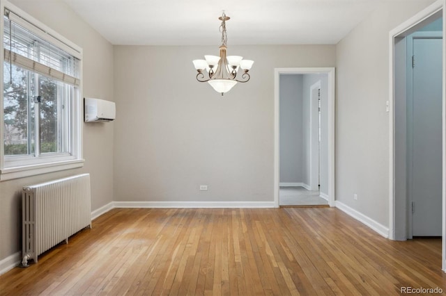 unfurnished room featuring a notable chandelier, light wood-style flooring, radiator, and a wall unit AC