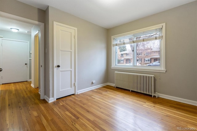 unfurnished bedroom featuring light wood-type flooring, radiator heating unit, and baseboards