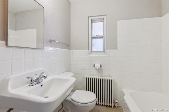 bathroom featuring radiator, a tub, a sink, tile walls, and toilet