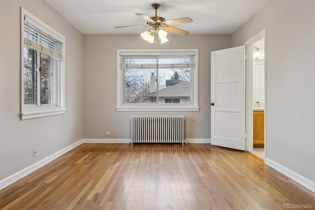 interior space with a wealth of natural light, ceiling fan, radiator heating unit, and light wood finished floors