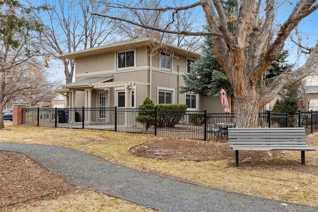 traditional style home featuring brick siding and a fenced front yard