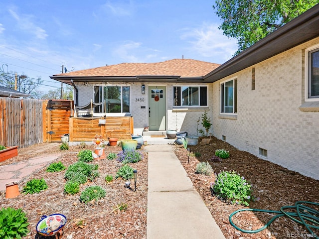 3450 N Harrison St, Denver, CO 80205 - property entrance featuring brick siding, roof with shingles, fence, and crawl space