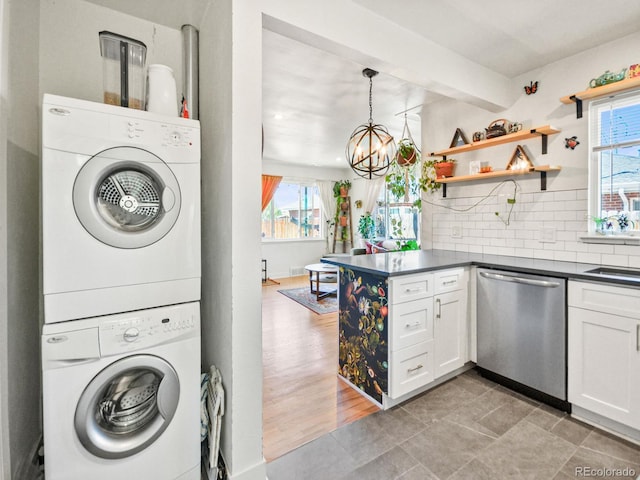 3450 N Harrison St, Denver, CO 80205 - laundry area with laundry area, an inviting chandelier, a healthy amount of sunlight, and stacked washer and dryer