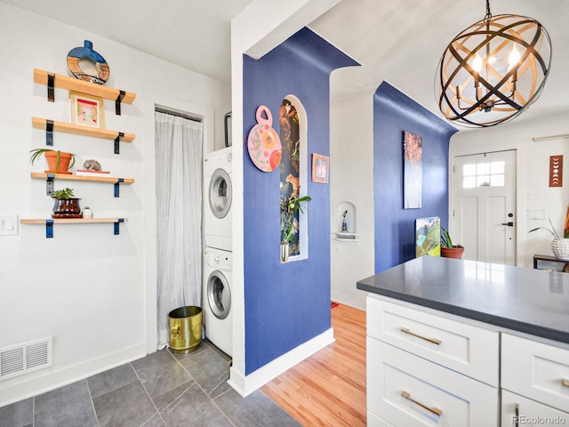 3450 N Harrison St, Denver, CO 80205 - washroom featuring laundry area, baseboards, visible vents, stacked washer and clothes dryer, and a notable chandelier