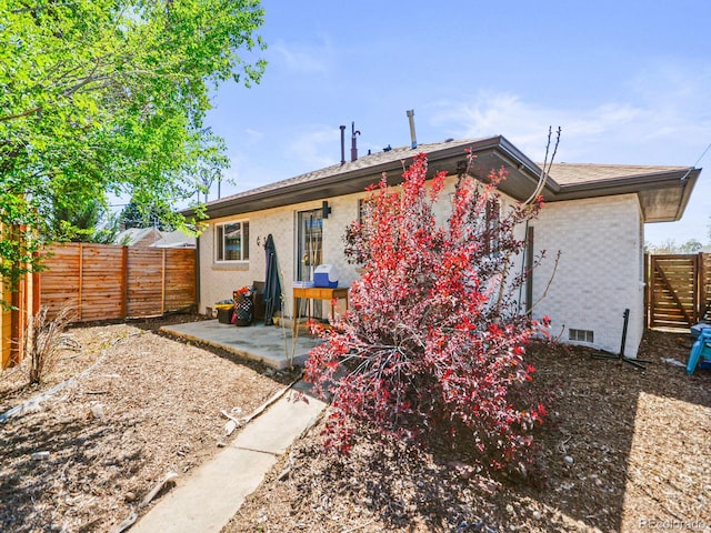 3450 N Harrison St, Denver, CO 80205 - rear view of property featuring a patio, brick siding, and a fenced backyard