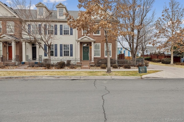 multi unit property with brick siding and a fenced front yard