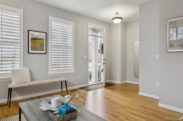 foyer with visible vents, wood finished floors, and baseboards