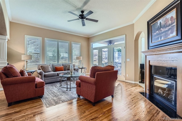 living area featuring a wealth of natural light, crown molding, a fireplace, and wood finished floors