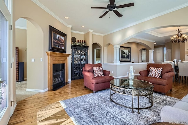 living room with recessed lighting, wood finished floors, baseboards, ornamental molding, and a glass covered fireplace