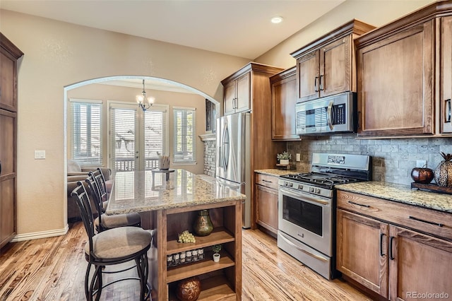 kitchen featuring open shelves, appliances with stainless steel finishes, light stone counters, and decorative backsplash