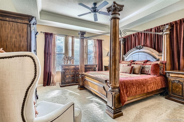 carpeted bedroom with ceiling fan, a tray ceiling, a textured ceiling, and ornamental molding