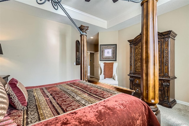 carpeted bedroom featuring a ceiling fan, a tray ceiling, crown molding, and baseboards