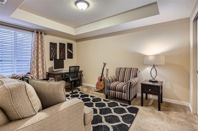 carpeted living area with a textured ceiling, a textured wall, a tray ceiling, and baseboards