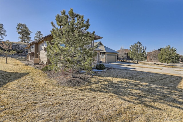 view of property hidden behind natural elements with a garage, driveway, and central AC unit