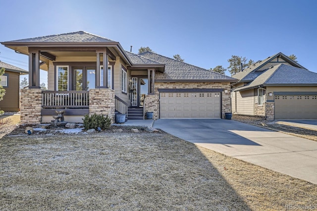 view of front of property with roof with shingles, covered porch, concrete driveway, a garage, and stone siding