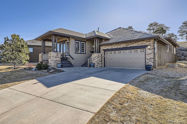 view of front of house with a garage, stone siding, and driveway