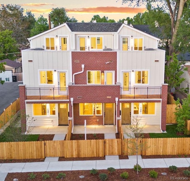 1048 Knox Ct, Denver, CO 80204 - view of front of home with a balcony, board and batten siding, a fenced front yard, and a patio area