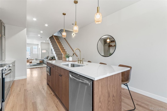 1048 Knox Ct, Denver, CO 80204 - kitchen with appliances with stainless steel finishes, a kitchen island with sink, open floor plan, light wood-type flooring, and recessed lighting